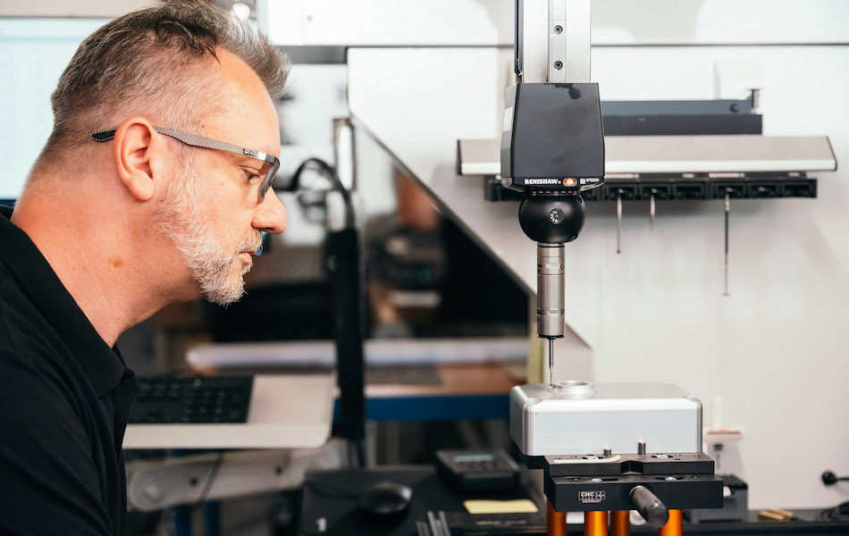 "Mitarbeiter führt Qualitätskontrolle mit Messgerät in technischer Werkstatt durch"